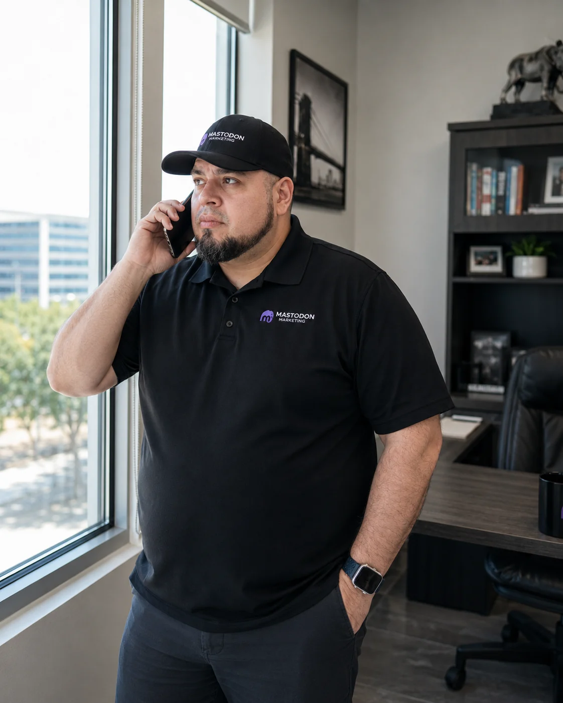 Alex Rocha, founder of Mastodon Marketing, on a client phone call at the firm's Pearland Texas office wearing a Mastodon Marketing branded polo and cap
